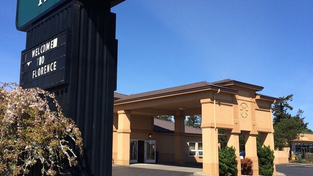 A Quality Inn with a welcoming sign, a covered entrance, and a clear sky.