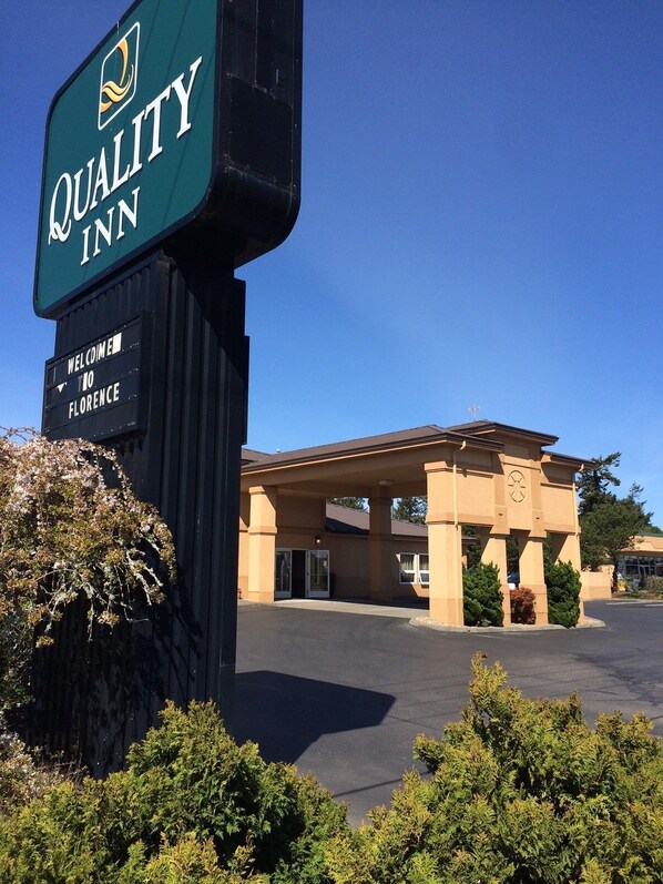 A Quality Inn with a welcoming sign, a covered entrance, and a clear sky.