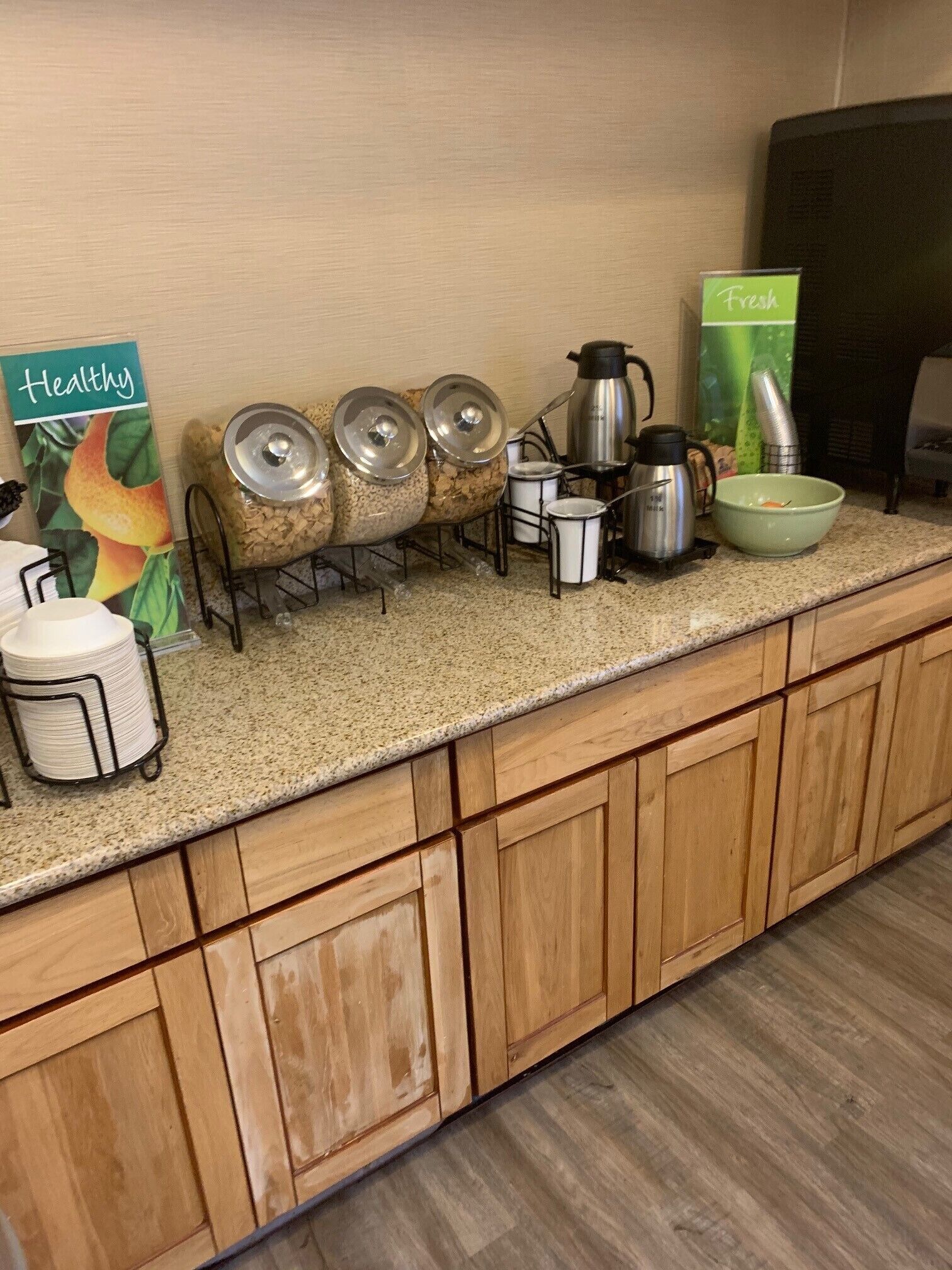 A kitchen counter with a coffee maker, a kettle, a bowl, and a sign that says "Fresh".