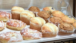 A display case with various baked goods, including muffins and pastries.