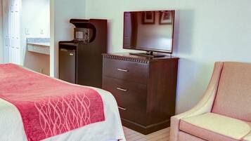 Hotellihuone, jossa on sänky, työpöytä, kahvinkeitin, televisio ja tuoli.