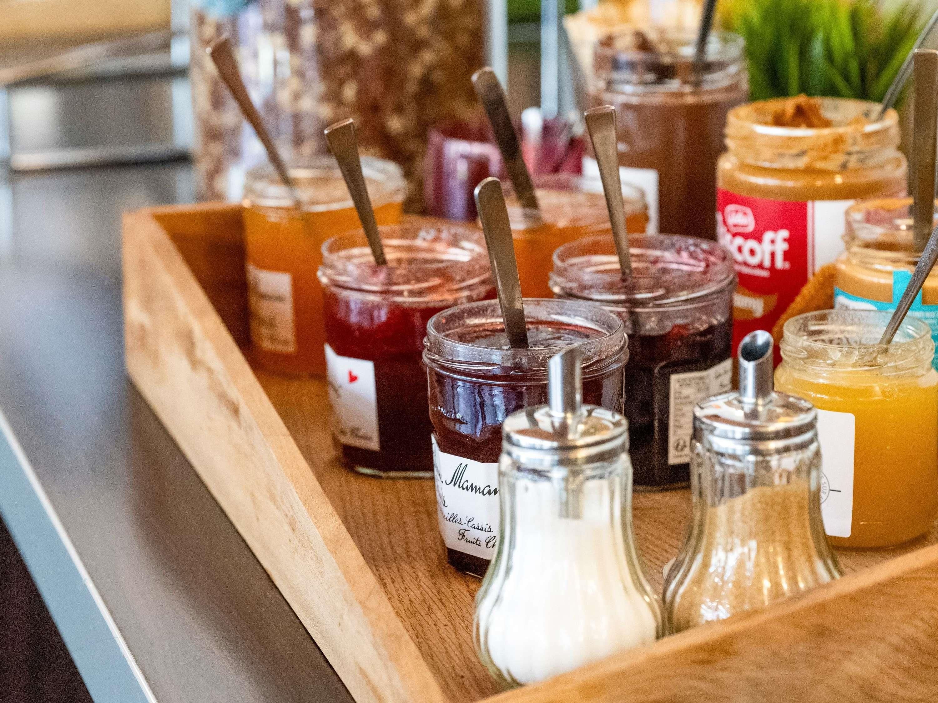 Una bandeja de madera con varios frascos de salsas y condimentos, incluyendo un frasco etiquetado 'Manhattan'.