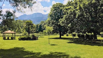 Un parque con un pabellón, mesas de picnic y un árbol grande.