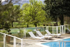 Un espace piscine avec des chaises longues et une barrière en verre.