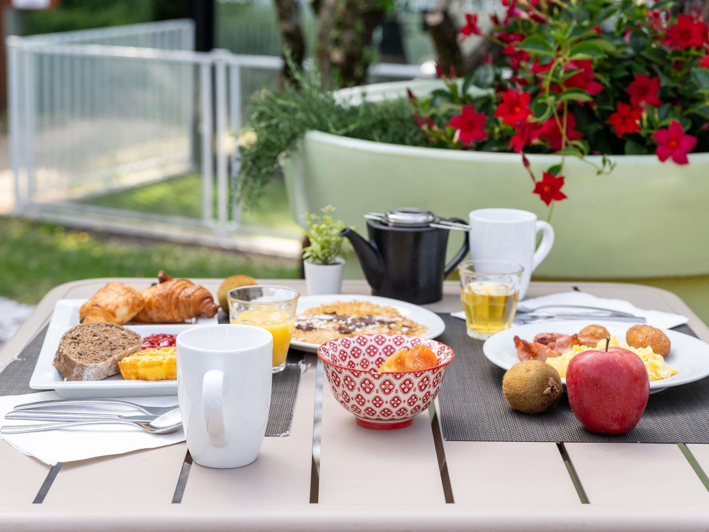Een ontbijttafel met croissants, brood, eieren en fruit.