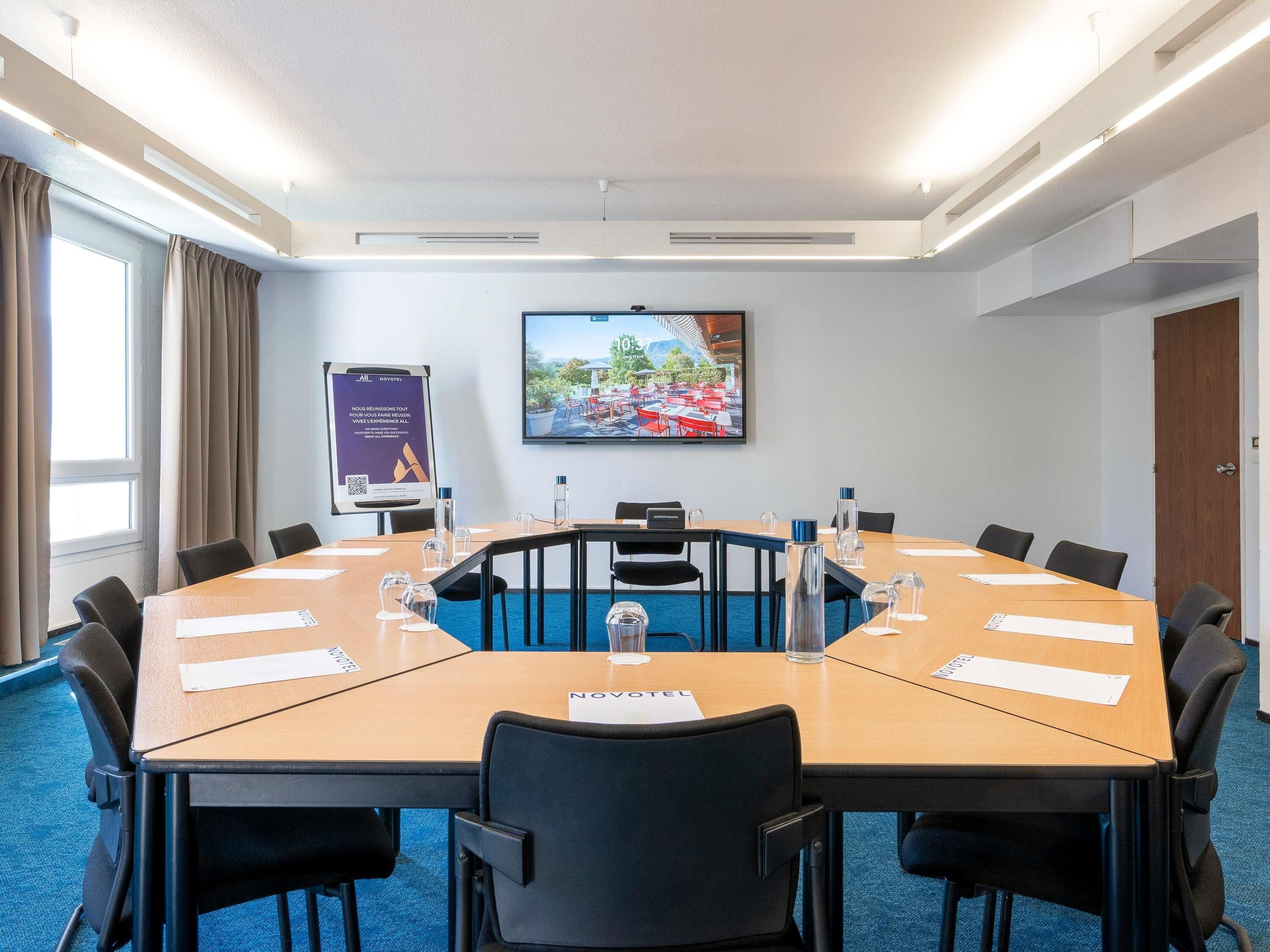 A conference room with a large table, chairs, a screen, and a banner.
