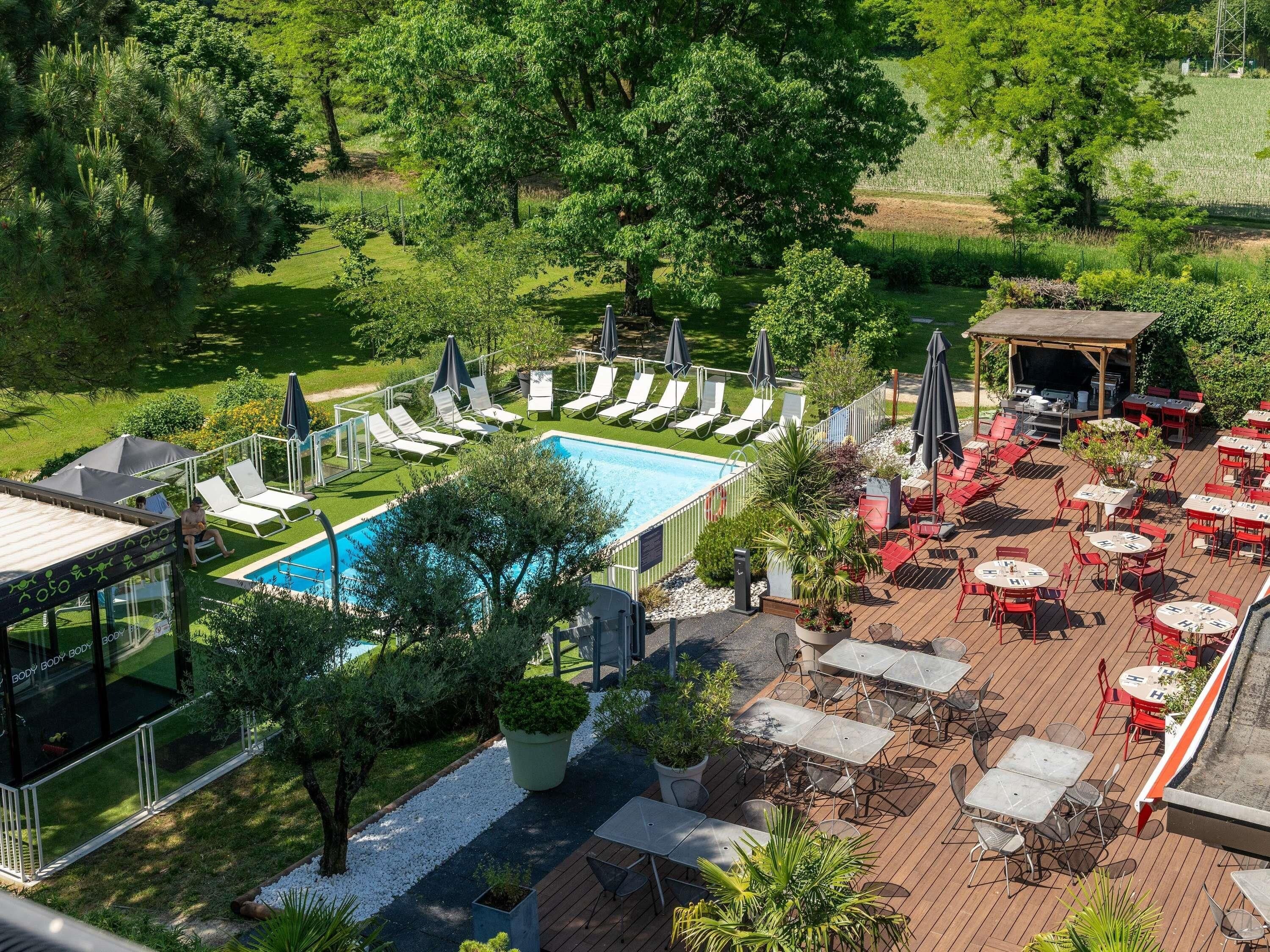 A pool area with lounge chairs, a barbecue, and outdoor seating.