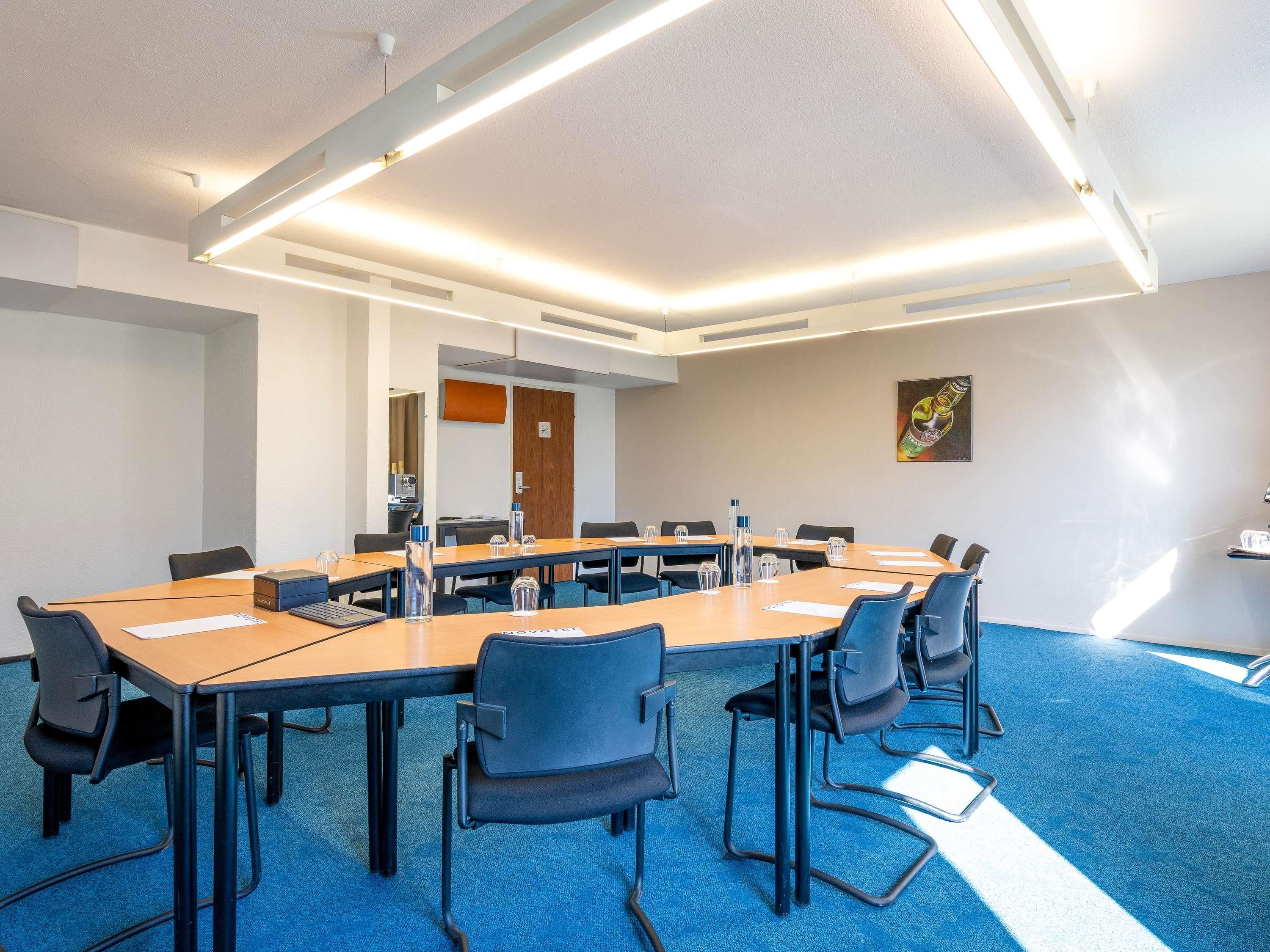 A conference room with a long table, chairs, and a blue carpet.