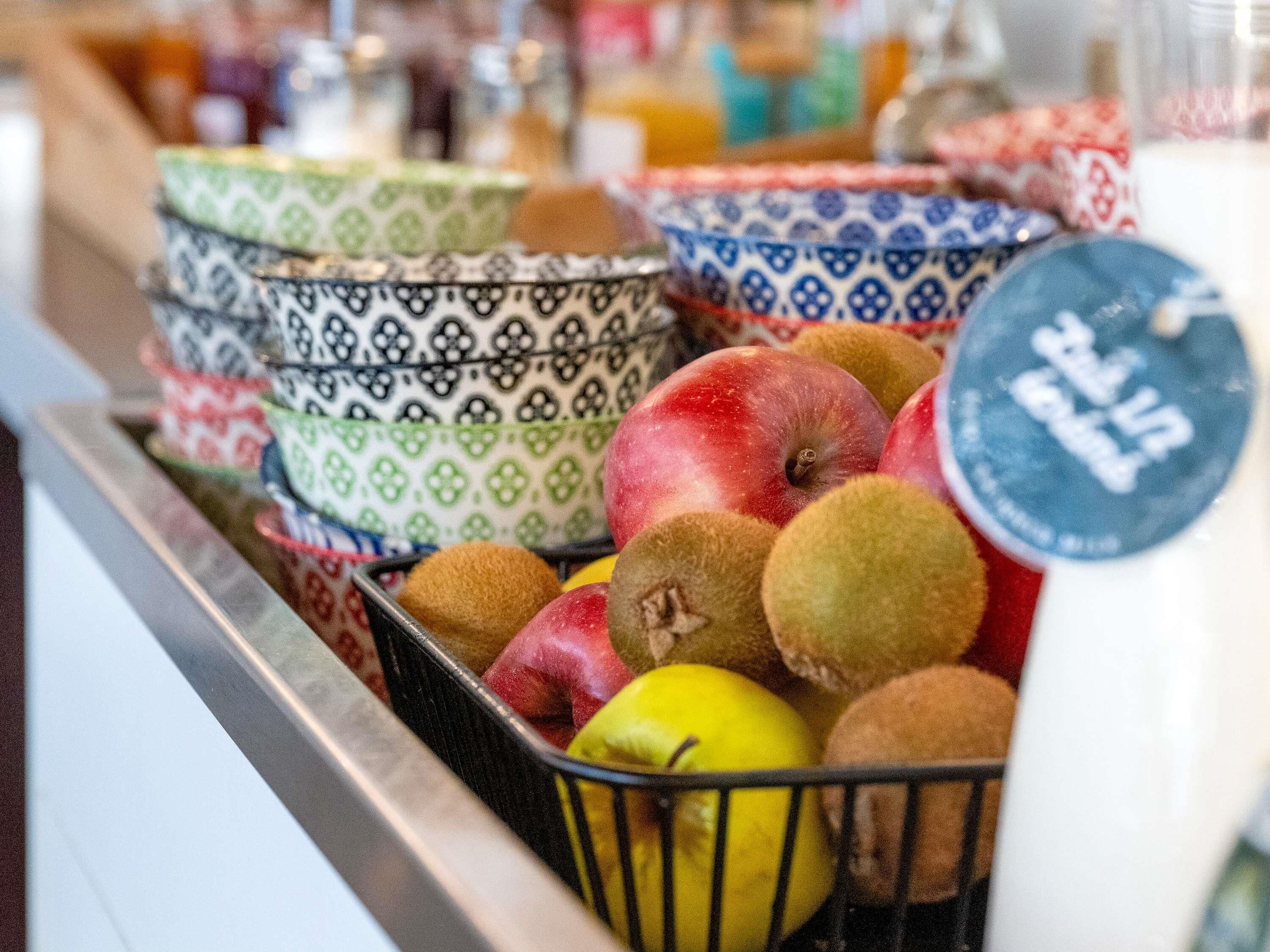 A basket filled with various fruits and bowls.