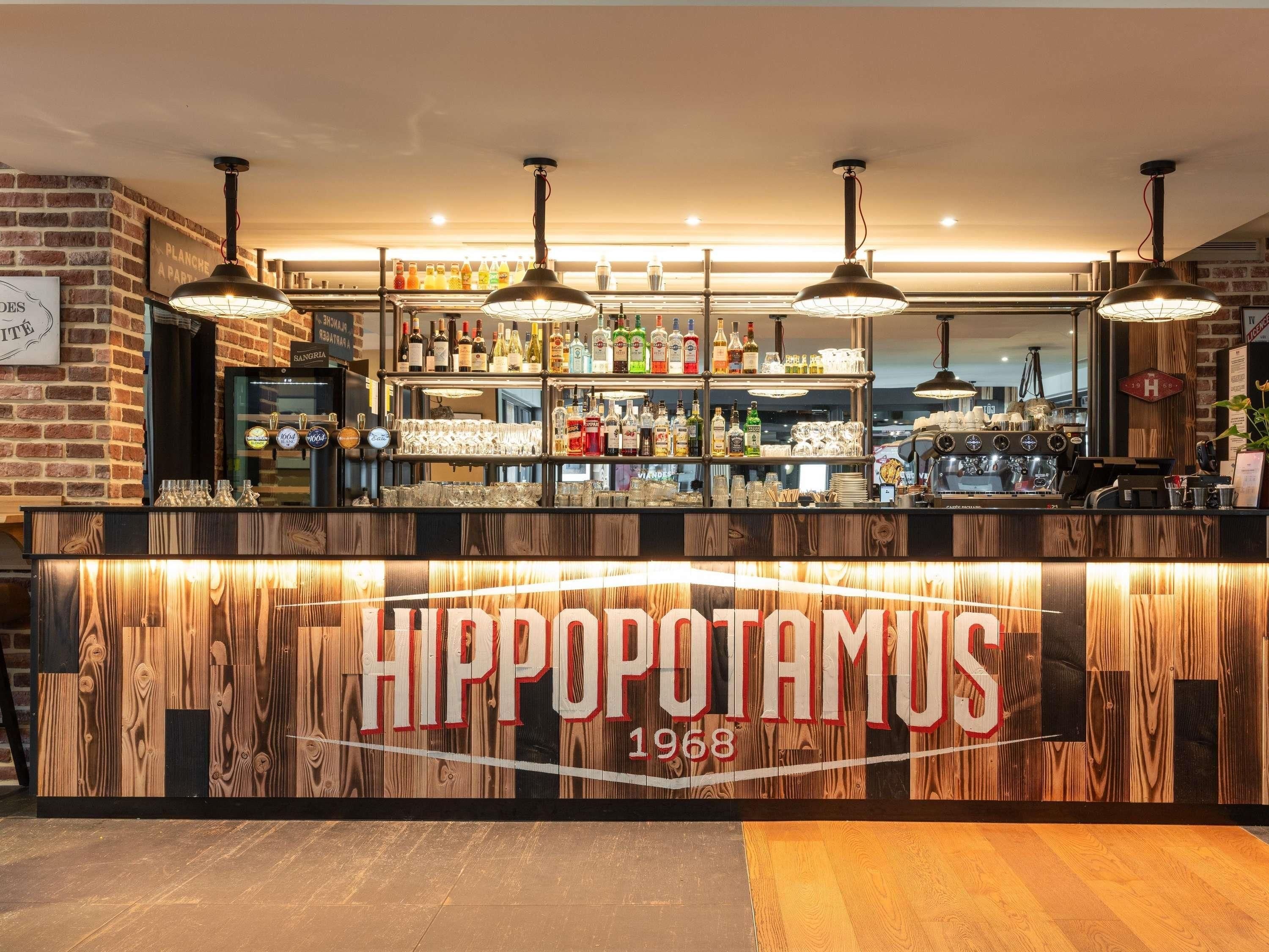 Un comptoir de bar au design en bois, sur lequel on peut lire en grand le nom « HIPPOPOTAMUS 1968 ».