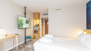 Ein Hotelzimmer mit Bett, Schreibtisch, Fernseher und einem durchgegangenen Tür sichtbaren Badezimmer.