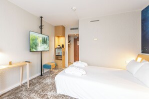 Een hotelkamer met een bed, een bureau, een televisie en een badkamer zichtbaar door een geopende deur.