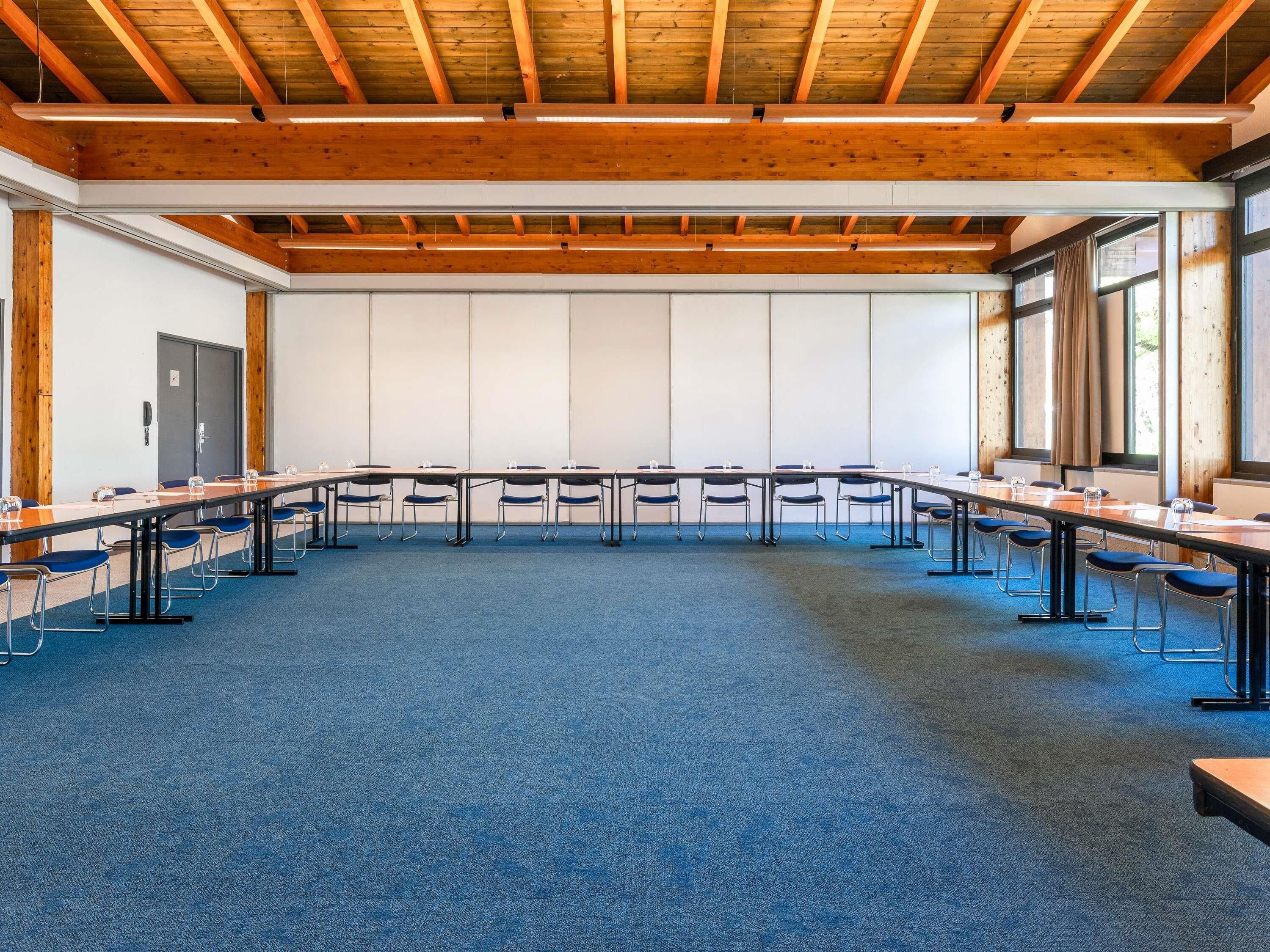 Sala de conferência com uma mesa comprida, cadeiras e teto de madeira.