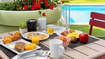 A breakfast table with croissants, waffles, fruit, and a glass of orange juice.