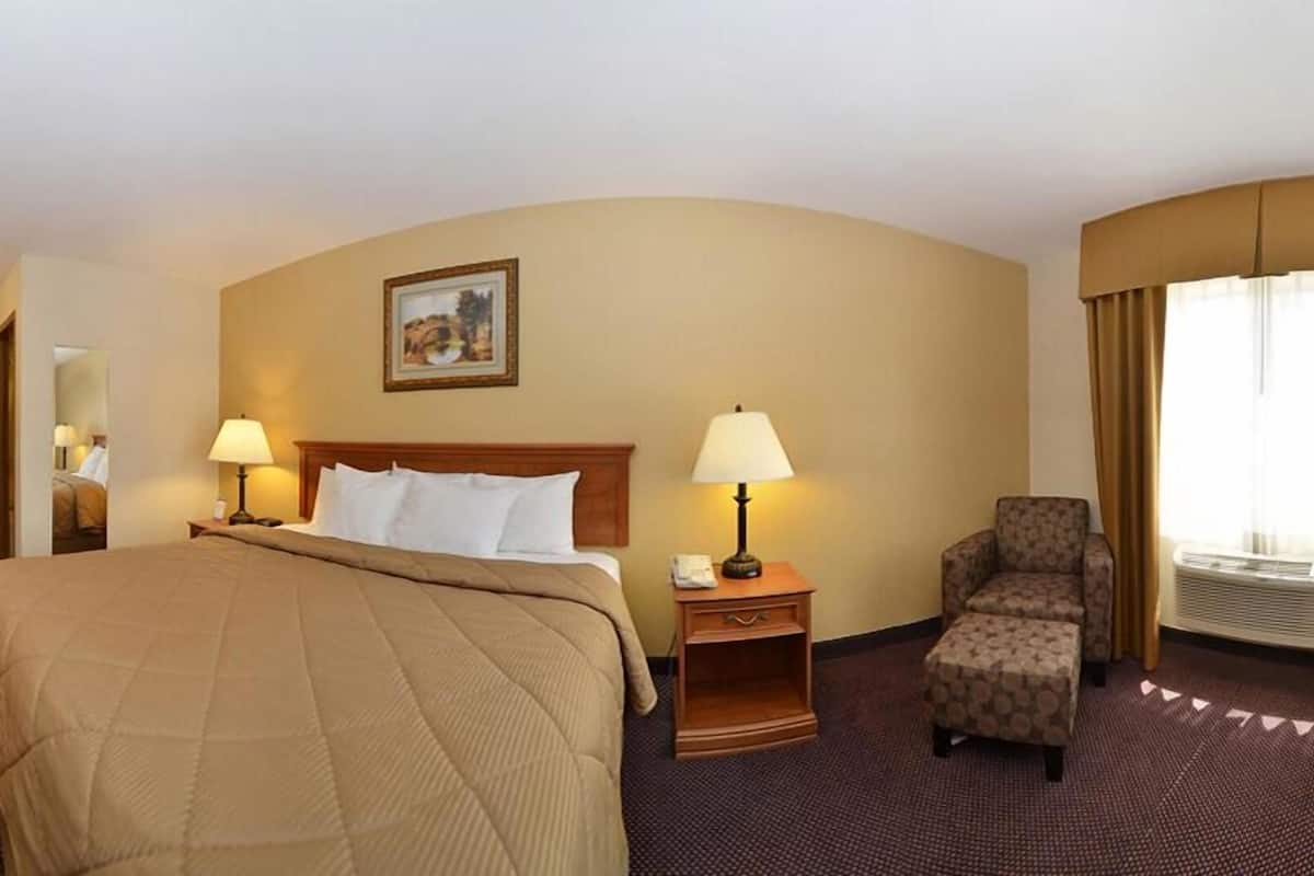 A hotel room with a large bed, two bedside tables with lamps, a chair, and a painting on the wall.