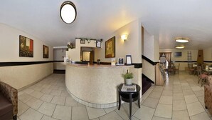 Un vestíbulo de hotel con una recepción, una escalera y un comedor.