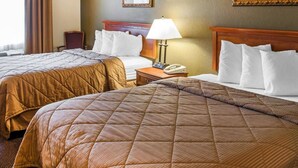 Habitación de hotel con dos camas tamaño queen, una mesita de noche con lámpara, teléfono y dos cuadros en la pared.