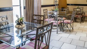 Un comedor con una mesa de vidrio, sillas a rayas y un televisor montado en la pared.