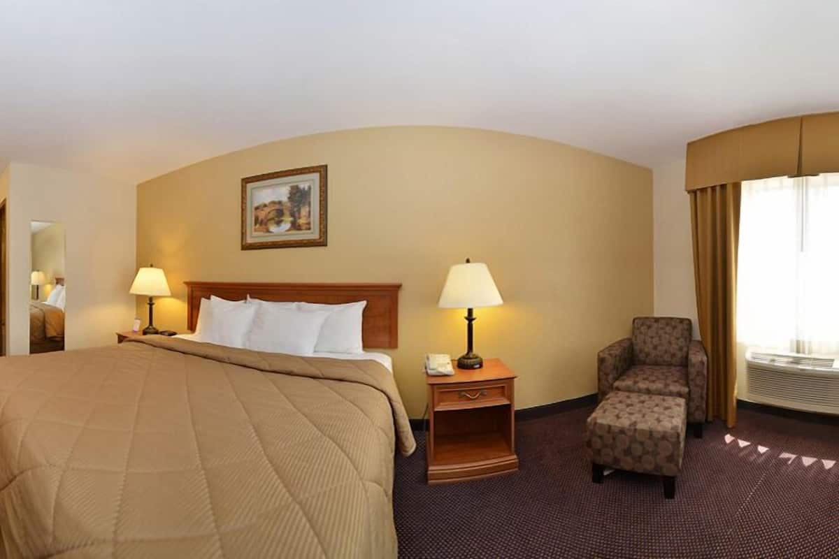 A hotel room with a large bed, two bedside tables with lamps, a chair, and a painting on the wall.