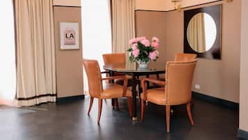 Un coin repas comprenant une table ronde, quatre chaises, un vase de fleurs, un miroir et des rideaux.