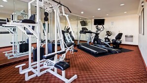 Una palestra con diverse attrezzature per esercizi, tra cui tapis roulant e macchinari per pesi, e un tappeto a motivi.