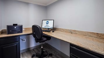 Un pequeño espacio de oficina con escritorio, silla, ordenador e impresora.