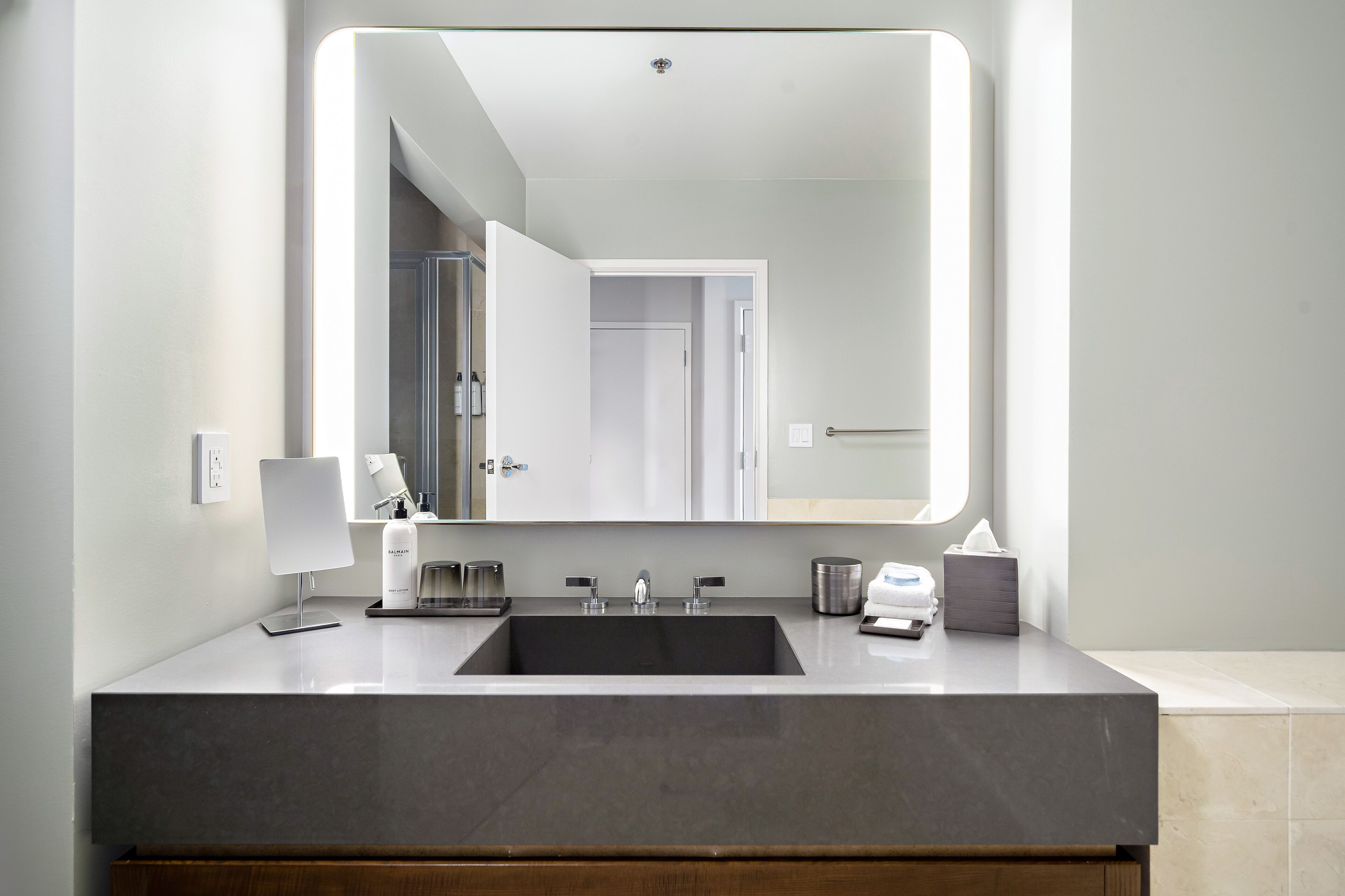 A modern bathroom with a large mirror, a sink, and a vanity.