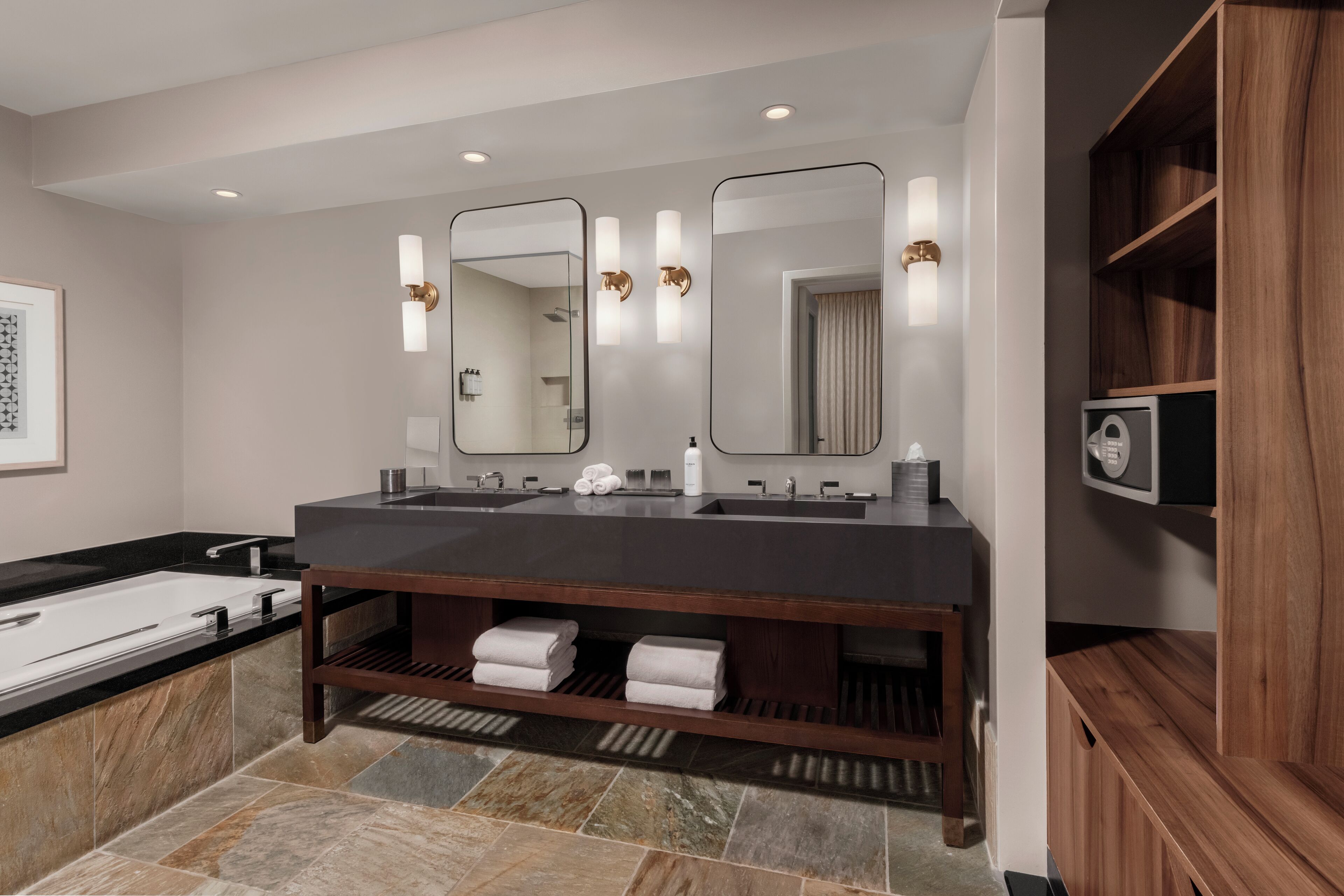 A modern bathroom with a double sink vanity, a large mirror, and a wooden vanity cabinet.