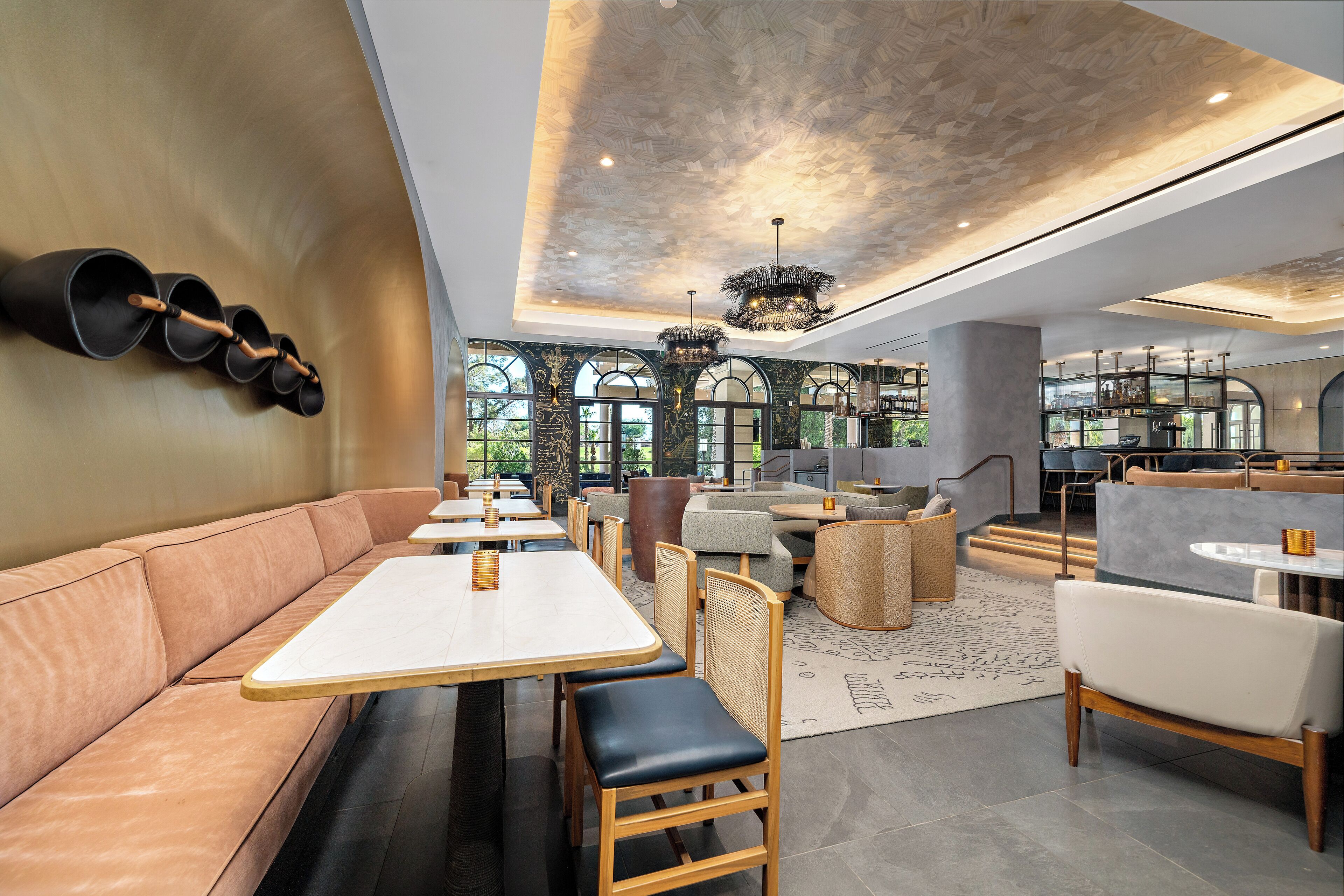A modern restaurant interior with leather seating, wooden tables, and a chandelier.