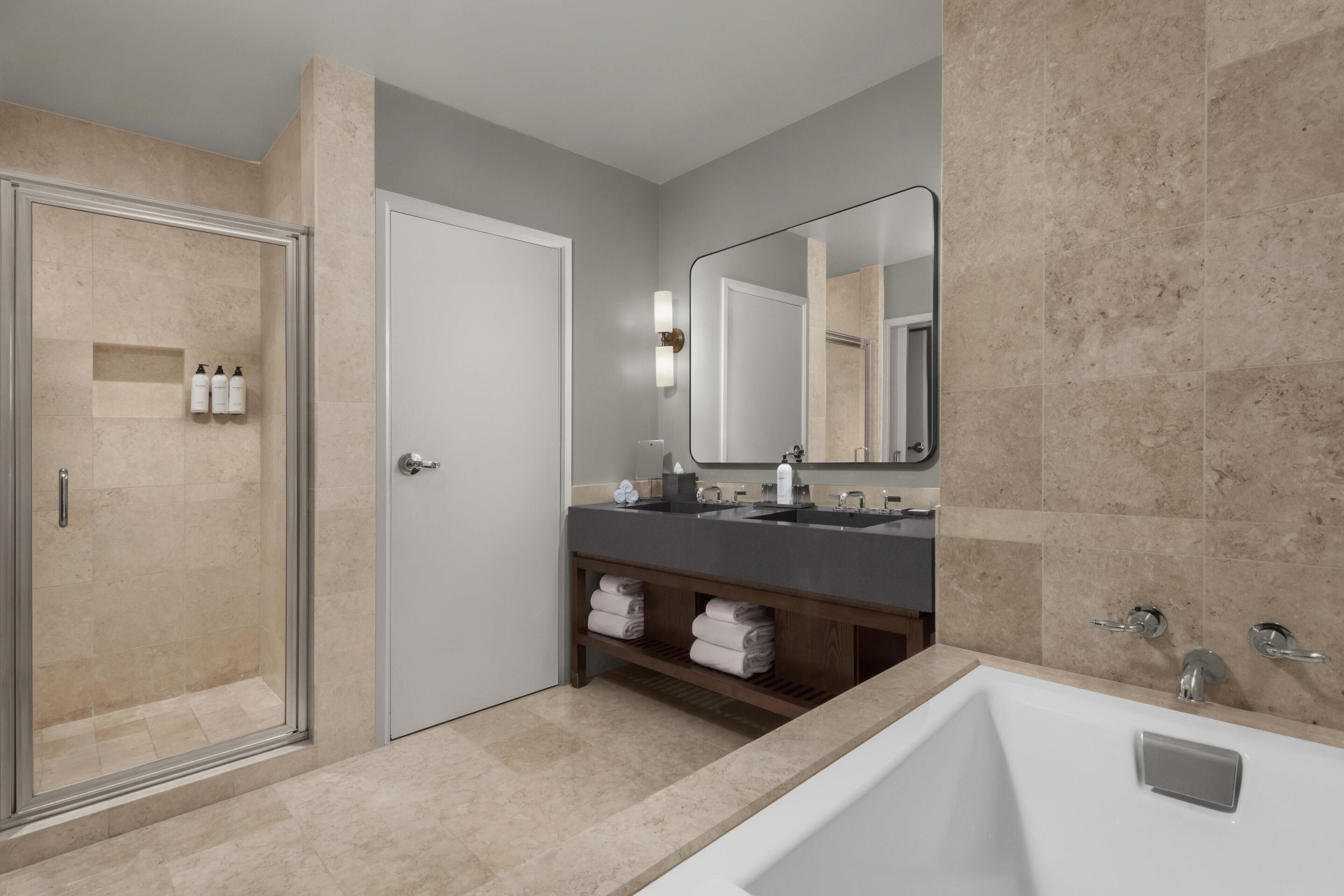 A modern bathroom with a glass shower enclosure, a double sink vanity, and a large bathtub.
