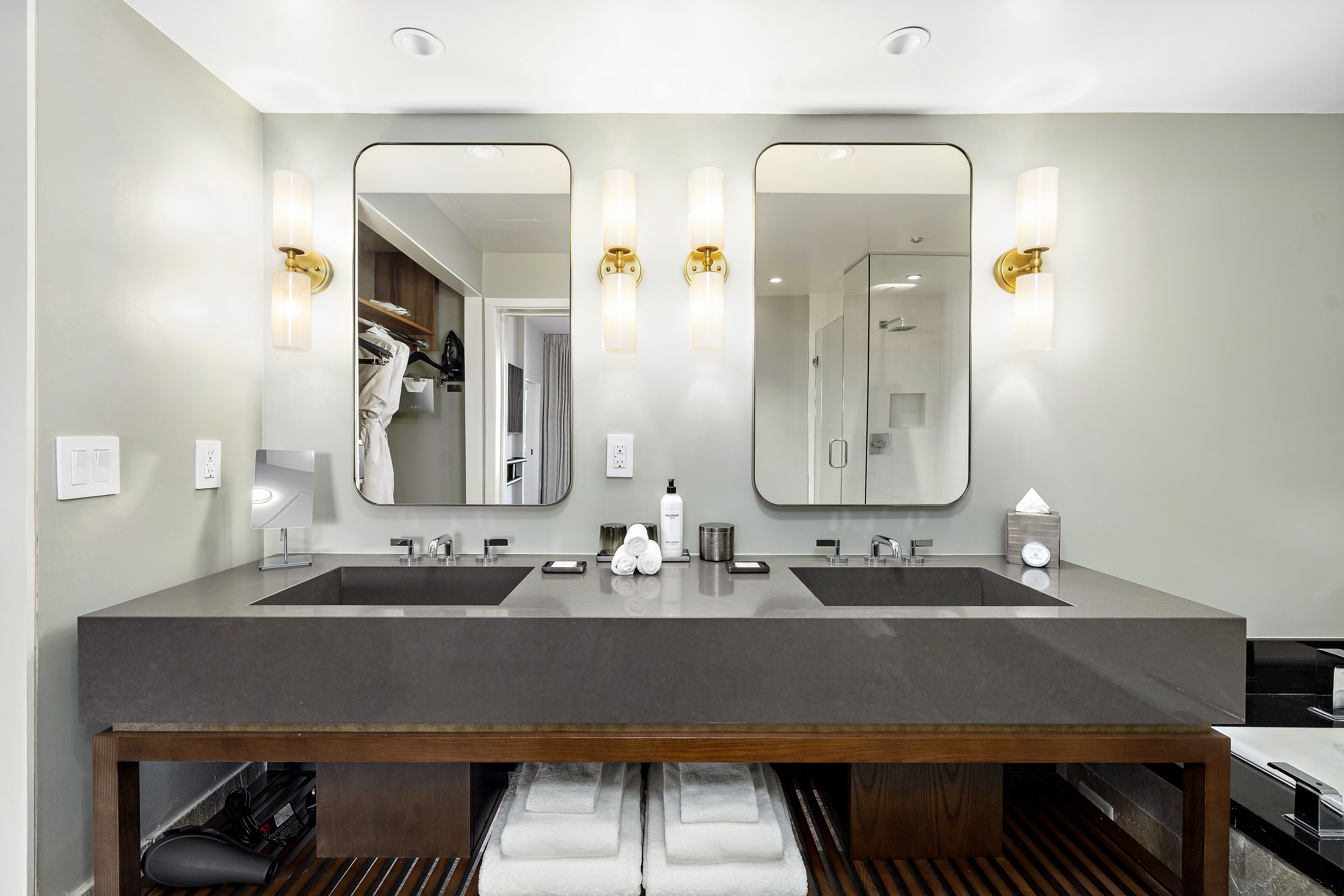 Un baño moderno con dos lavamanos, espejos grandes e iluminación empotrada.