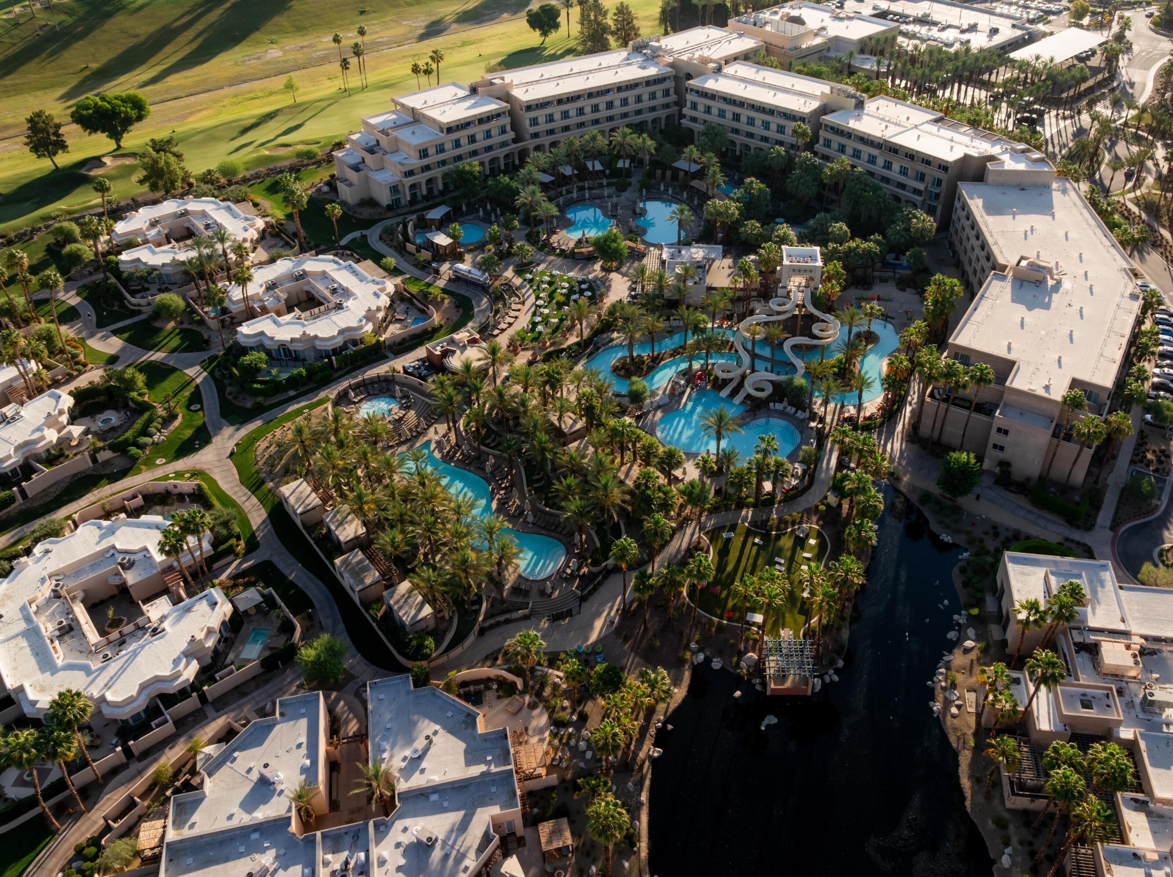 A resort with multiple swimming pools, palm trees, and a large building complex.