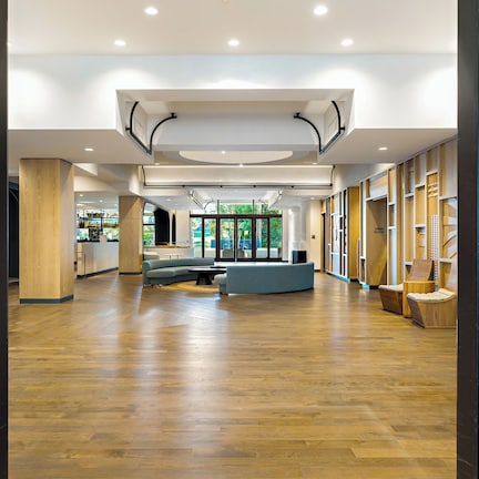 A spacious lobby with a curved seating area, wooden paneling on the walls, and a view of the outdoors through large windows.
