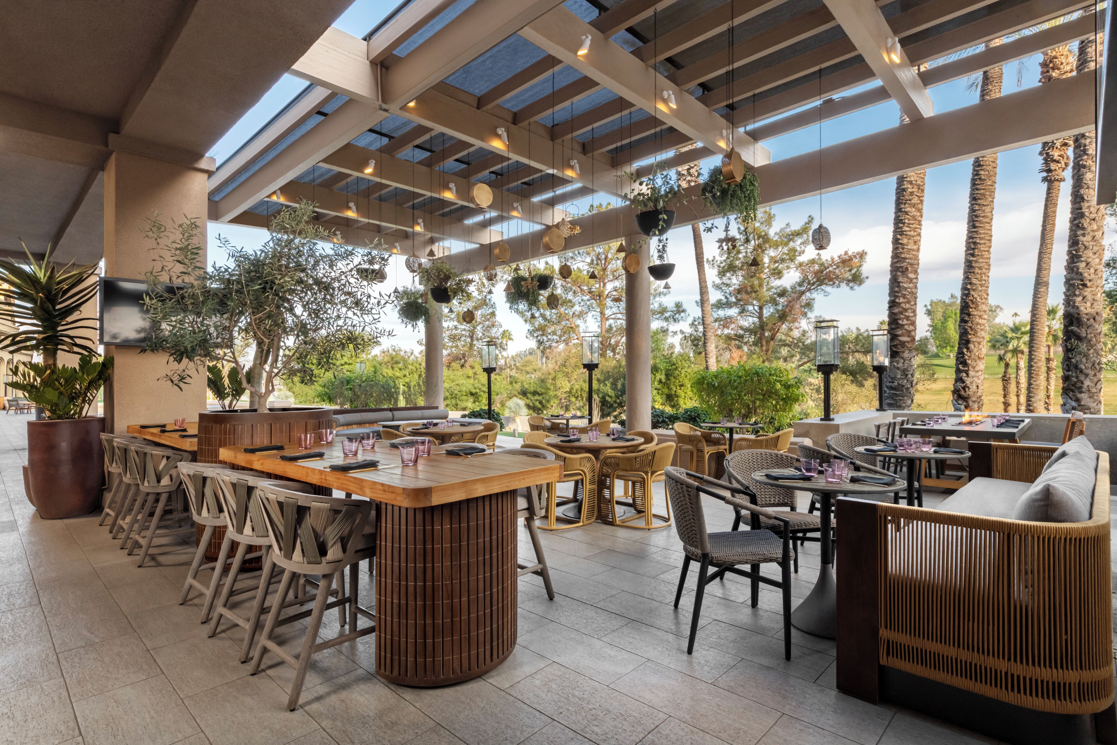 Ein Terrassenbereich im Freien mit Bar, Sitzgelegenheiten und Topfpflanzen.