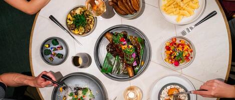 A round dining table with various dishes, utensils, and a candle.