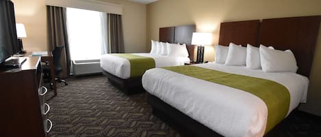 A hotel room with two beds, a desk with a chair, a TV, and a window with curtains.