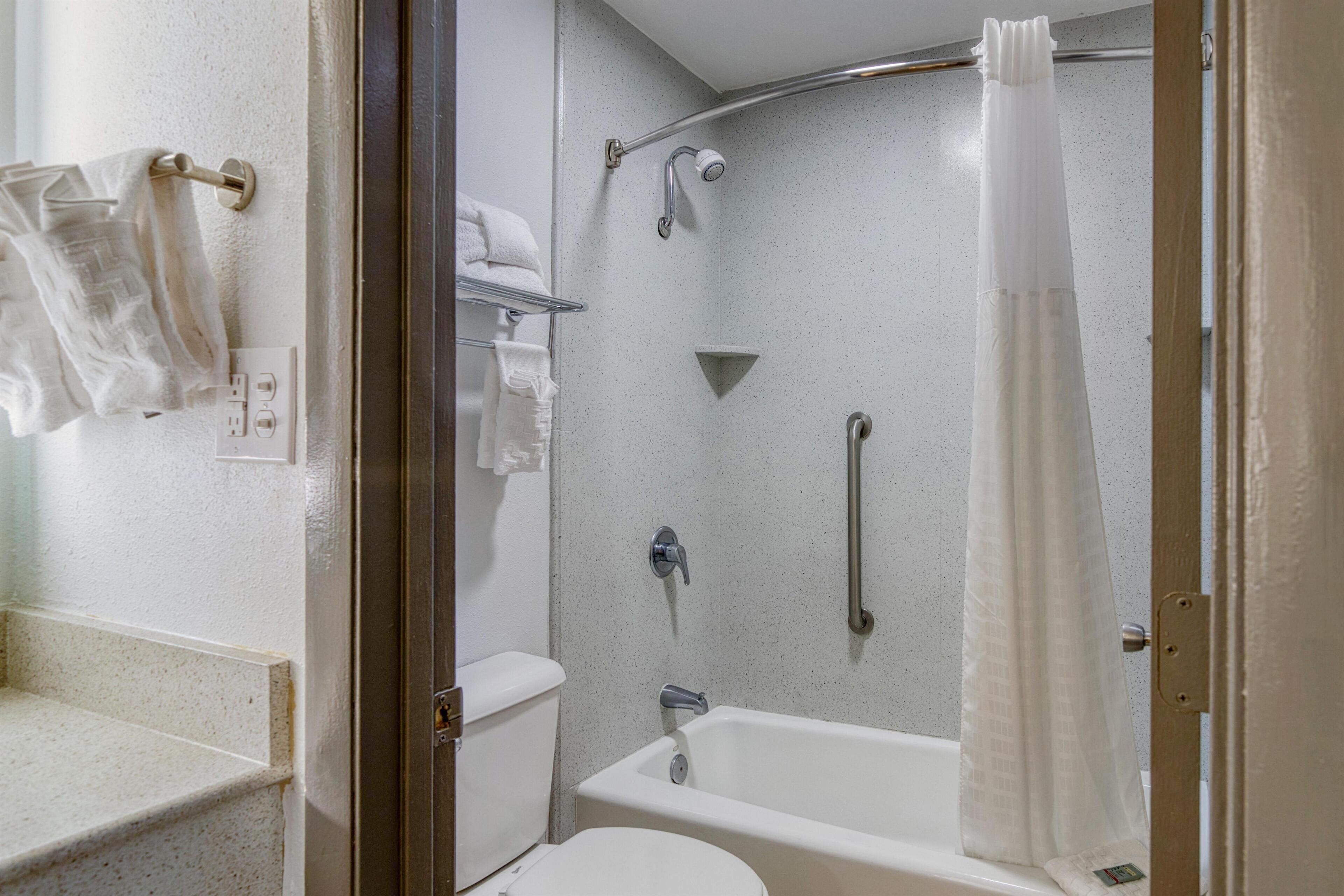 A modern bathroom with a shower, toilet, and a towel rack.