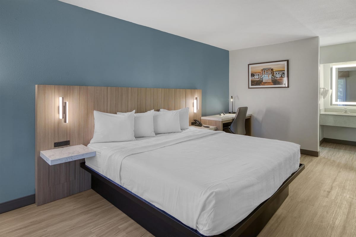 A modern hotel room with a large bed, a desk, and a chair.