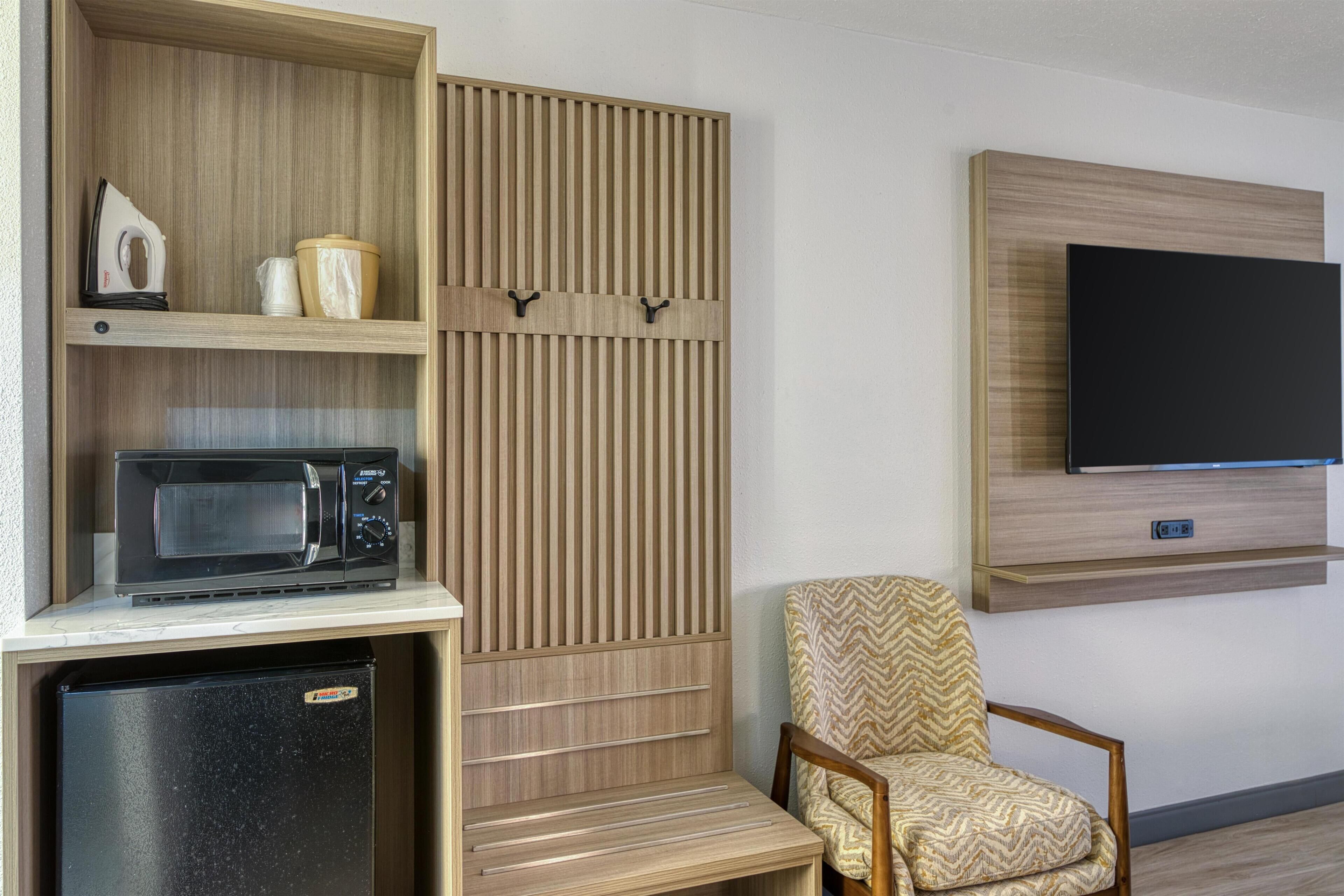 Ein kompakter Wohnbereich mit Mikrowelle, Kühlschrank und einem an der Wand befestigten Fernseher.