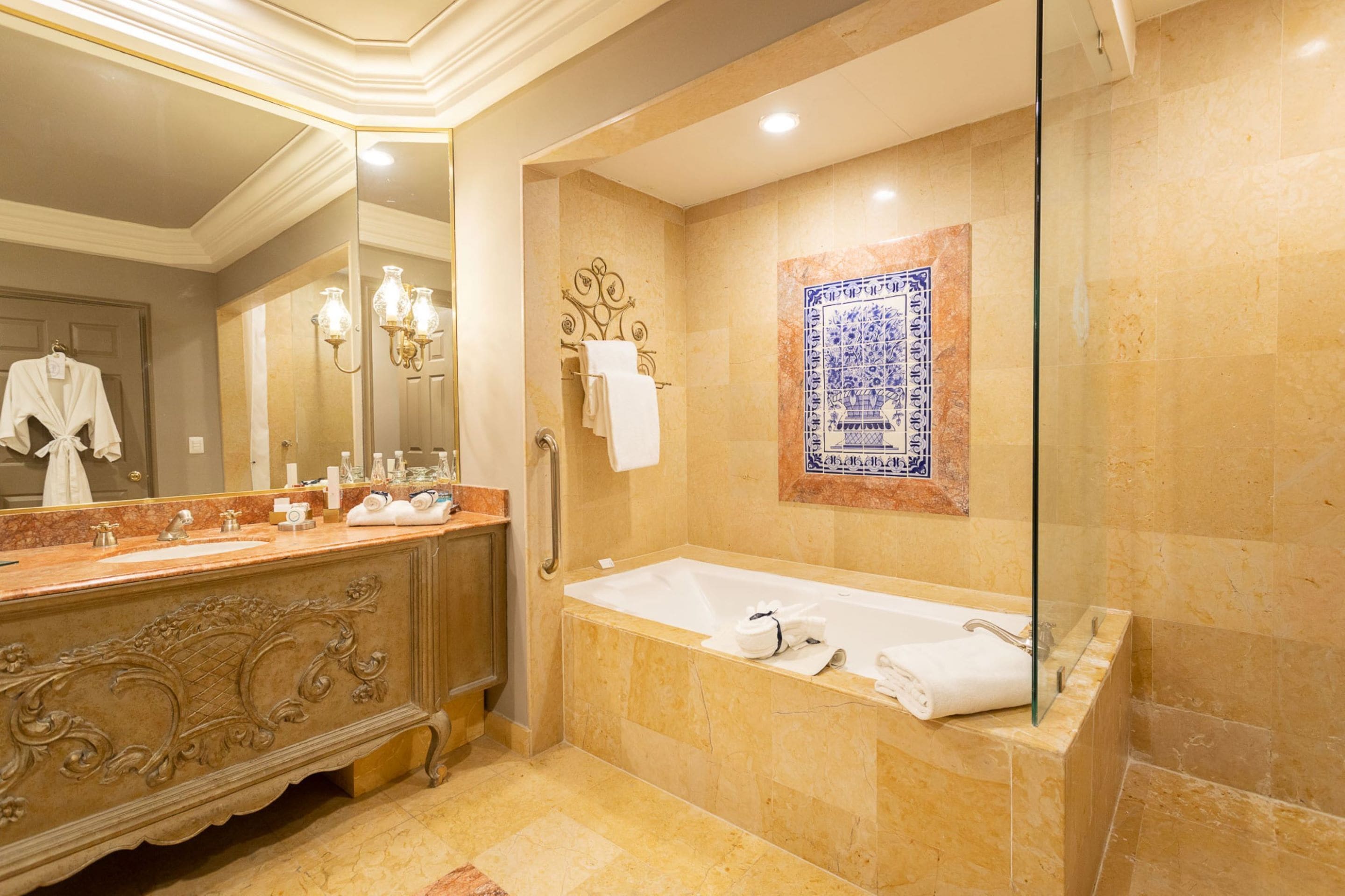 A luxurious bathroom with a marble vanity, a freestanding bathtub, and a decorative tile wall.