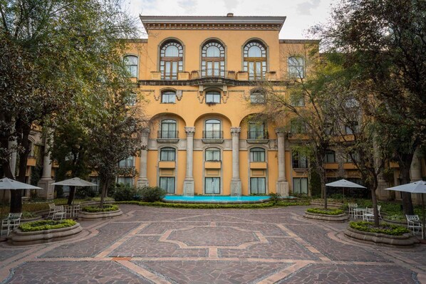 A courtyard with a central fountain, surrounded by trees and outdoor seating. - Quinta Real Monterrey (San Pedro Garza García)