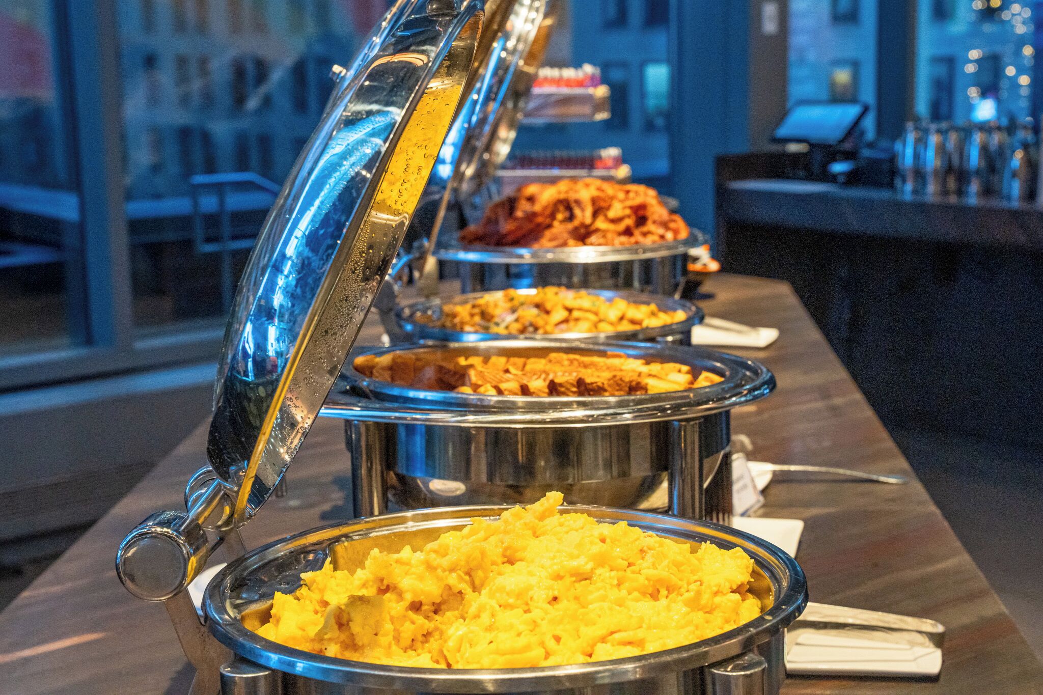 A buffet with various dishes in metal serving containers, arranged on a counter.
