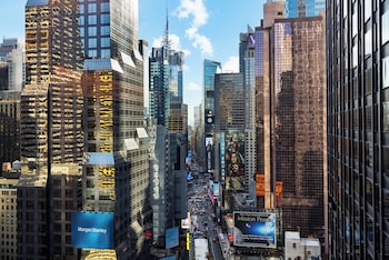 A cityscape with tall buildings, busy streets, and various billboards. at M Social Hotel New York Times Square