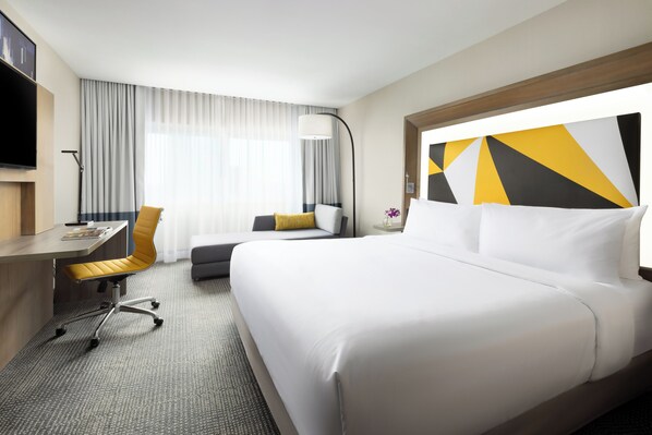 A hotel room with a bed, a desk, a chair, a TV, and a large window with curtains. - M Social Hotel New York Times Square (New York)
