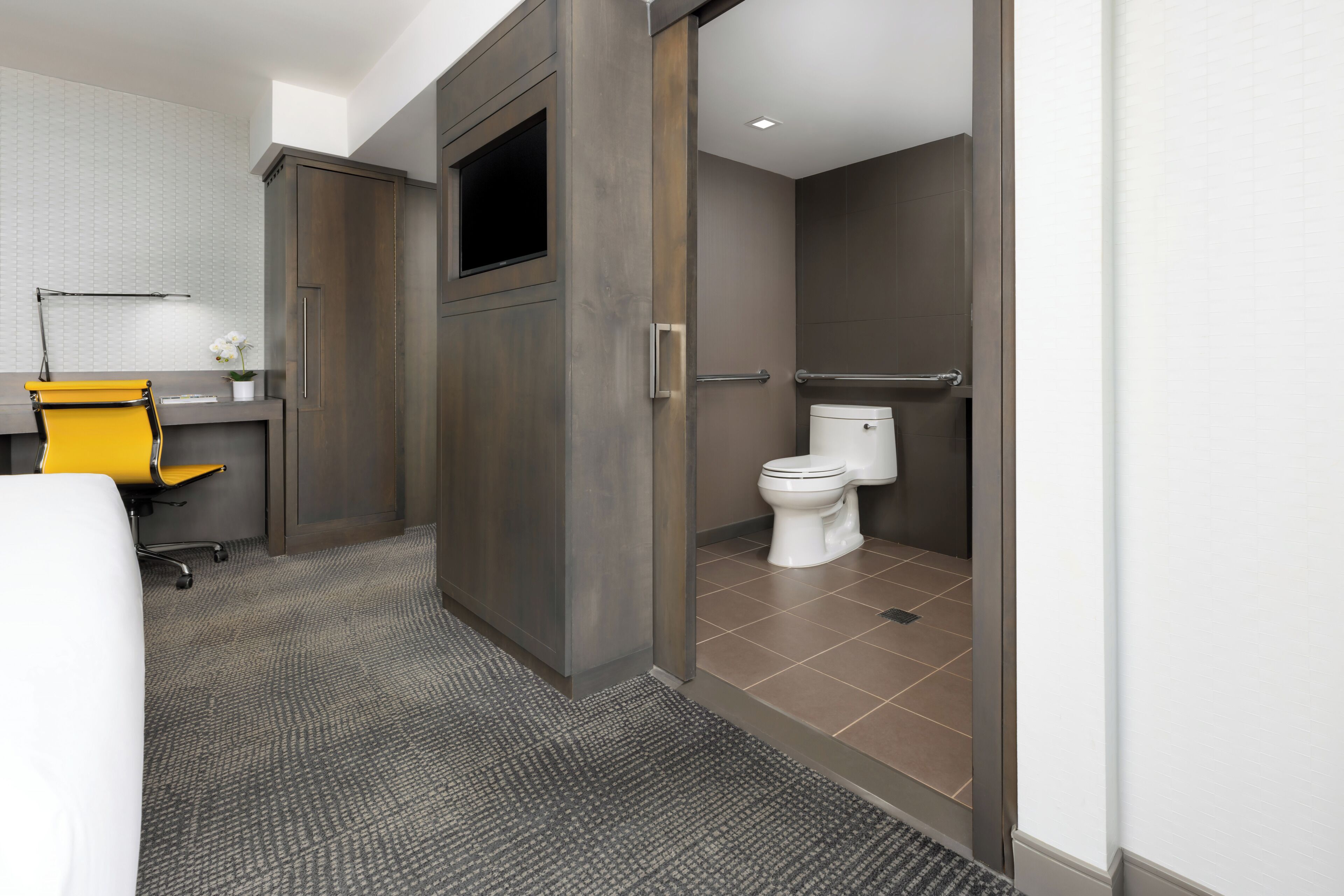 A modern bathroom with a toilet, shower, and a small sink area.