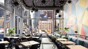 A modern restaurant with large windows, black chairs, and tables.