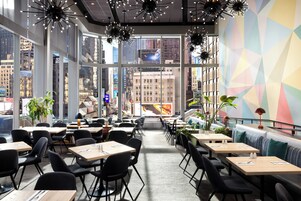 A modern restaurant with large windows, black chairs, and tables.