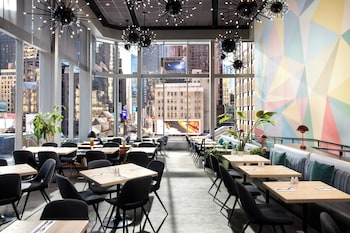 A modern urban plaza with a reflective water feature, surrounded by high-rise buildings and flags. at M Social Hotel New York Times Square