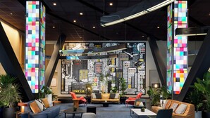 A modern lounge area with a cityscape view, comfortable seating, and ambient lighting.