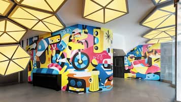 Experience the dynamic atmosphere of this modern space, featuring a geometric ceiling and vibrant murals.